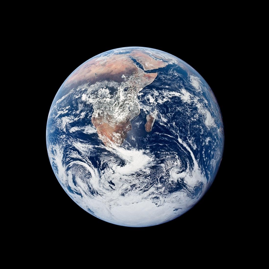 Photograph: the whole Earth, fully lit, against black space. Africa and Arabia are at the top, Madagascar to the right, white swirls of cloud below and the Antarctic ice cap at the bottom.
